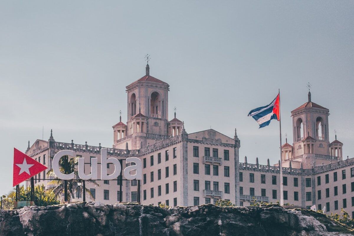 The historic Hotel Nacional de Cuba in Havana, with a Cuban flag flying and a large “Cuba” sign in the foreground.