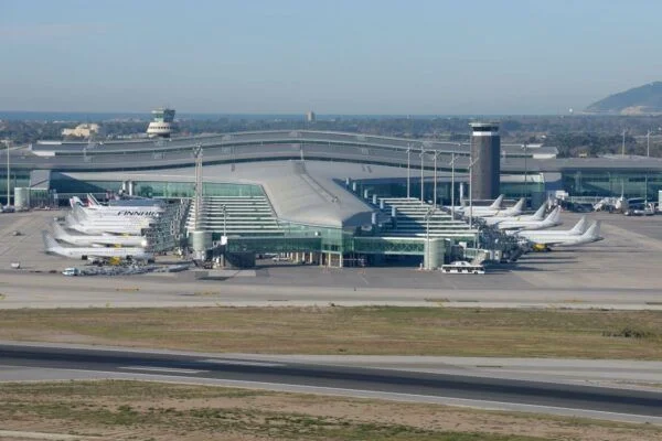 Aerial view of Barcelona El Prat Airport terminal with multiple aircraft parked at the gates.