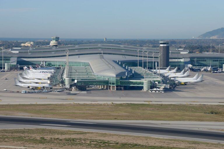Spain Travel And Tourism News 10 Aerial view of Barcelona El Prat Airport terminal with multiple aircraft parked at the gates.