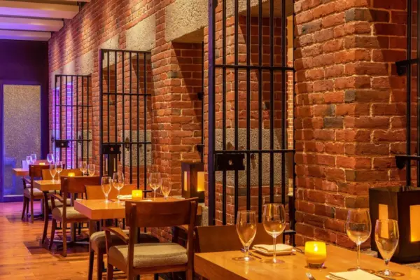 Places To Stay 49 Dining area in a luxury prison hotel with exposed brick walls and original cell bars.