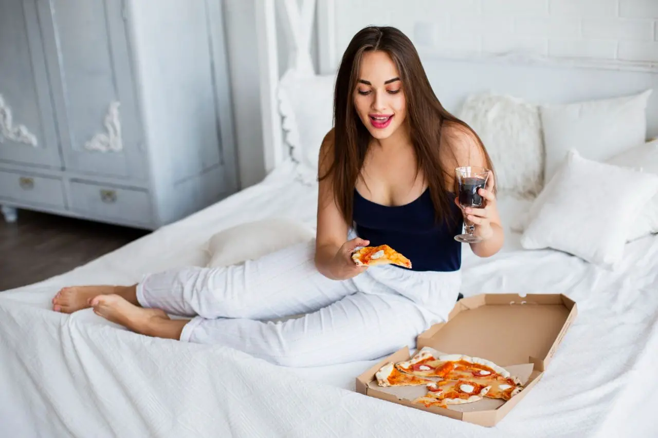 food delivery to hotel room, woman enjoys pizza in room