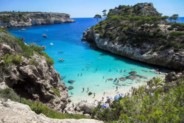 Spain Travel And Tourism News 18 White sandy beach of Mallorca with sea color from turquoise to dark blue, tourists swimming