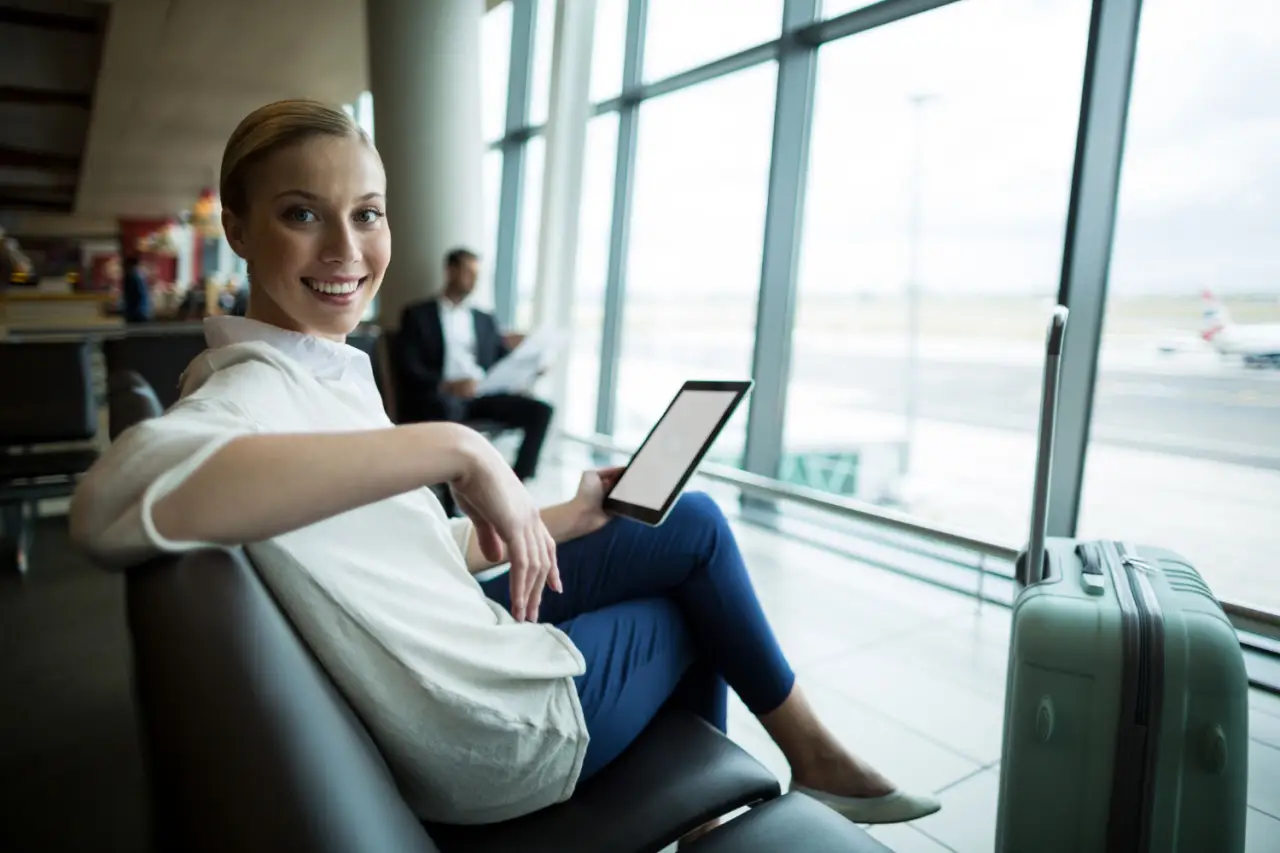 woman passenger at an airport using tablet while waiting her flight