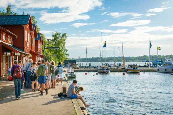 People walking and sitting by the water in Fjäderholmarna, one of the islands closest to Stockholm city