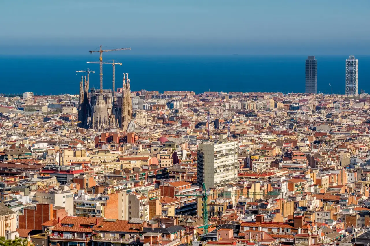 Researchers Analyze Airbnb'S Influence On Barcelona'S Housing And Tourism 11 Barcelona cityscape aerial view to the city with sagrada familia, houses, and Mediterranean sea visible