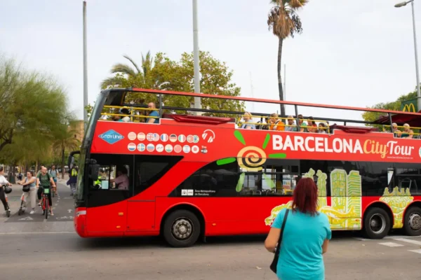 Red color open-top Barcelona City tour bus with tourists