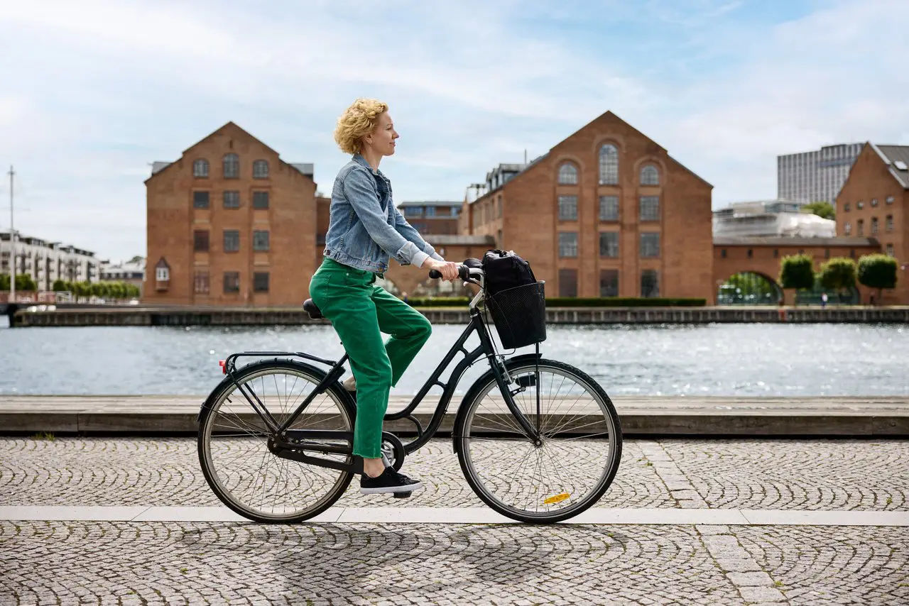 Woman is biking in Copenhagen by the canal