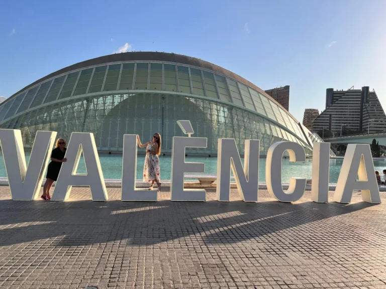 mother and daughter posing to camera at the Valencia sign in City of Arts and Sciences complex
