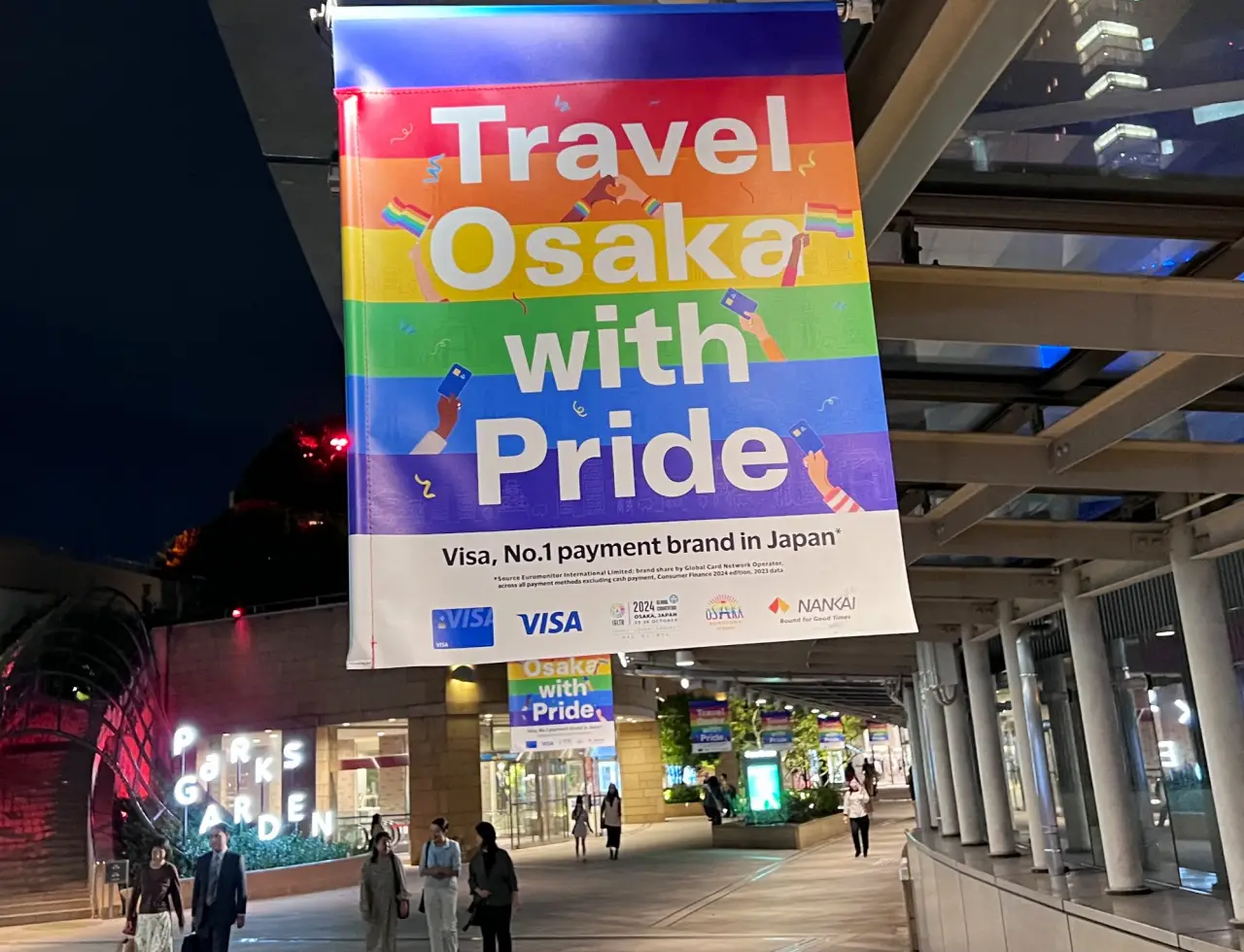 Colorful banner at the IGLTA 2024 Global Convention in Osaka, Japan, displaying the message ‘Travel Osaka with Pride,’ promoting inclusivity in LGBTQ+ tourism.