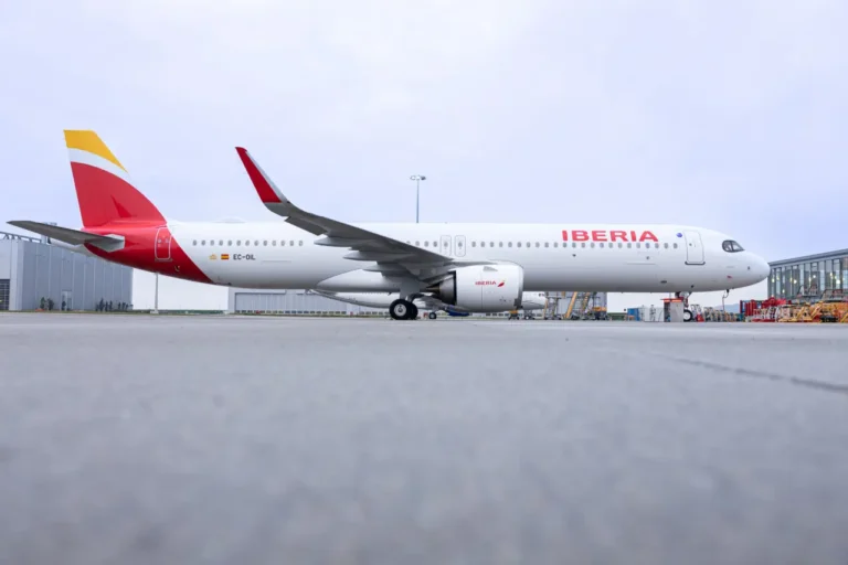 Spain Travel And Tourism News 16 A side view of an Iberia Airbus A321XLR aircraft (registration EC-OIL) parked on the tarmac during delivery, showing the white fuselage with Iberia’s red and yellow tail design, engine fairings, and ground handling equipment in the background.