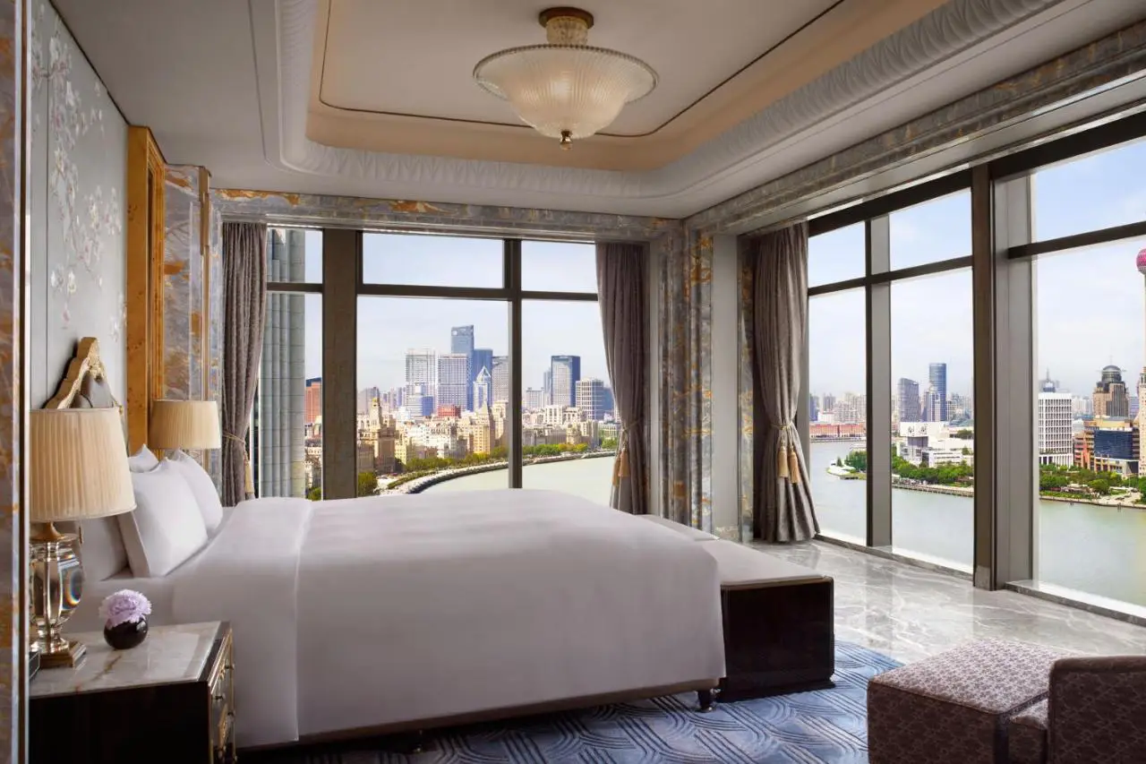 Luxurious hotel room at The St. Regis on the Bund, Shanghai, with stunning panoramic views of the Huangpu River and the city skyline.