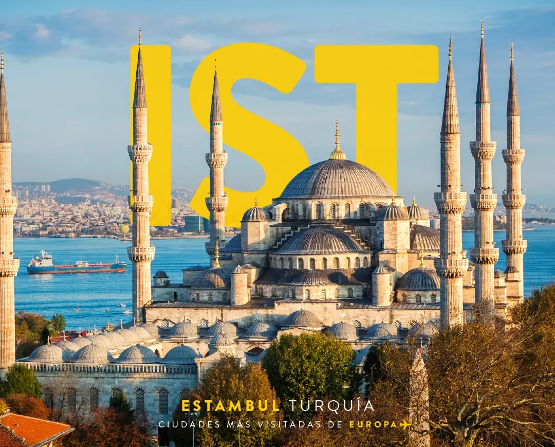 View of the Blue Mosque with minarets in Istanbul, Turkey, with a bright blue sky in the background and the sea, ships, and the “IST” abbreviation in large yellow text overlay.