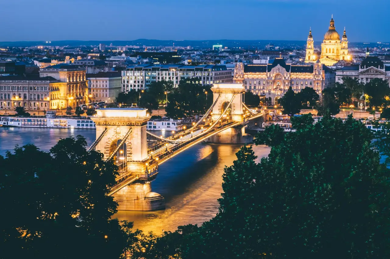 Budapest’s Chain Bridge illuminated at night, with the Danube River and St. Stephen’s Basilica in the background