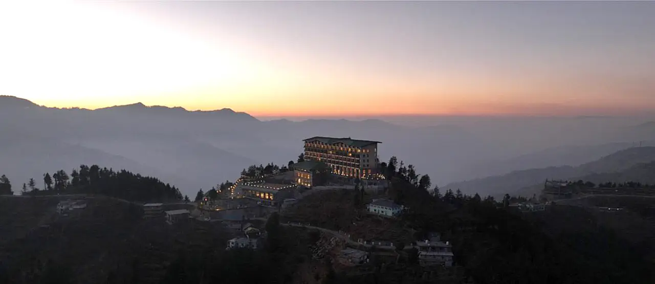 DusitD2 Fagu hotel illuminated at dusk with Himalayan mountains in the background