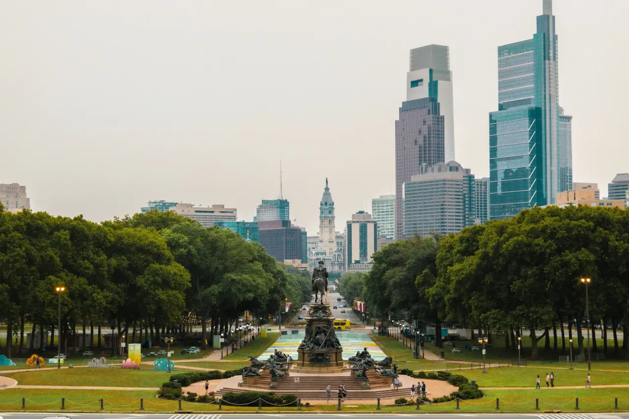 A scenic view of Philadelphia’s skyline, framed by lush greenery and iconic architecture, including City Hall.