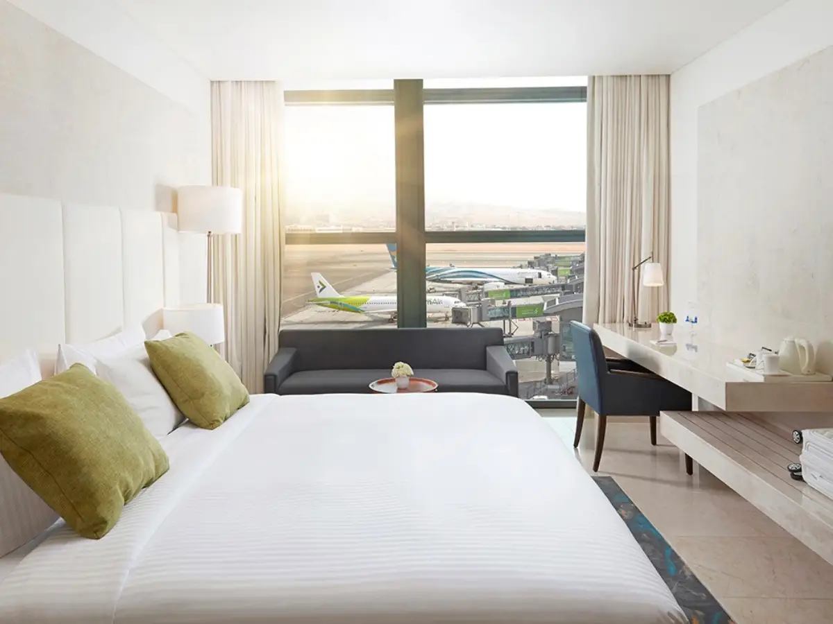 Hourly hotel room near an airport with a comfortable bed, workspace, and a view of the runway, ideal for layovers and short stays.