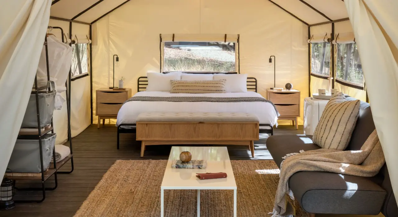Interior of a luxury tent at AutoCamp Yosemite with a cozy bed and seating area.