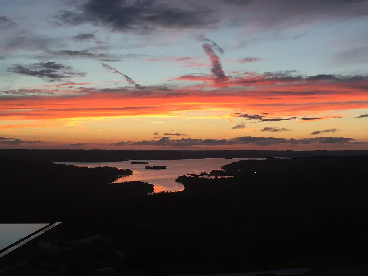 A breathtaking sunset over Table Rock Lake in Branson, Missouri, with vivid orange, pink, and purple hues reflecting on the water.