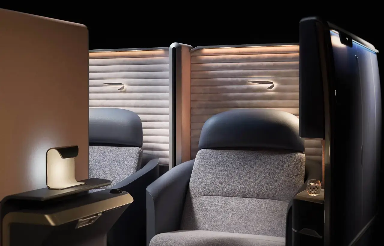 British Airways’ new First Class seat showcasing luxurious design and privacy, featuring curved walls, soft panelling, and elegant ambient lighting.
