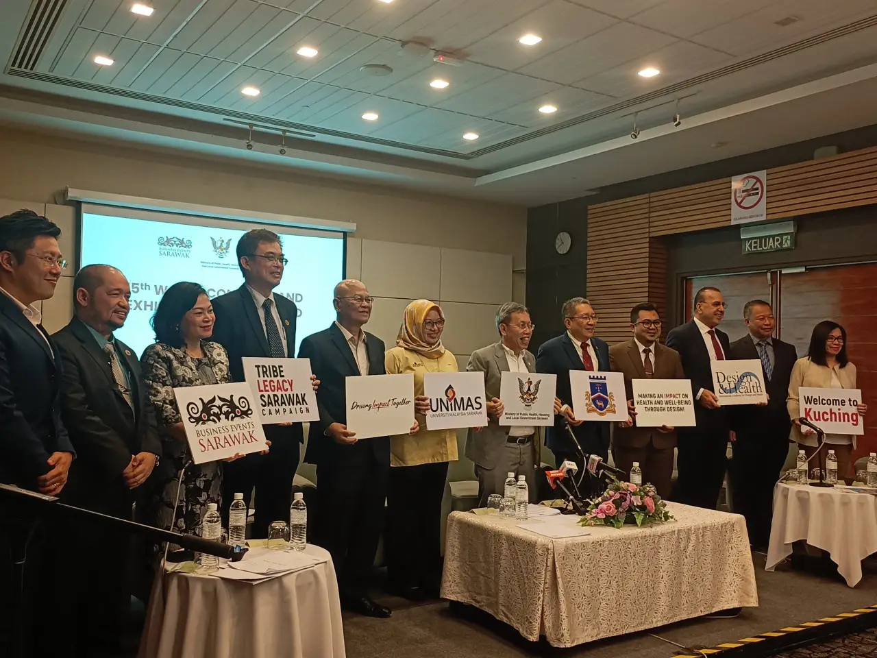 Group of Congress organizers and collaborators posing with banners promoting the 15th World Congress and Exhibition on Design and Health 2026 in Kuching, Sarawak.