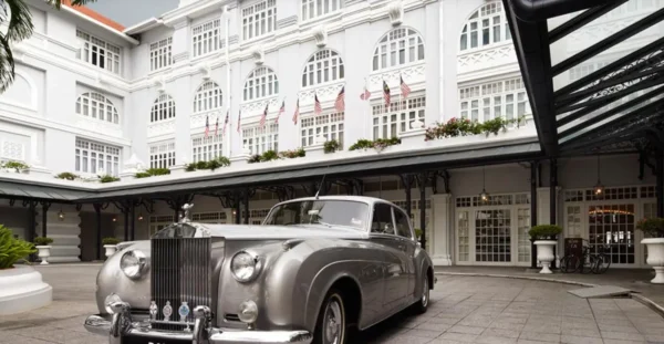 A vintage Rolls-Royce parked in front of the Eastern & Oriental Hotel, a historic colonial-style luxury hotel in Penang, Malaysia.