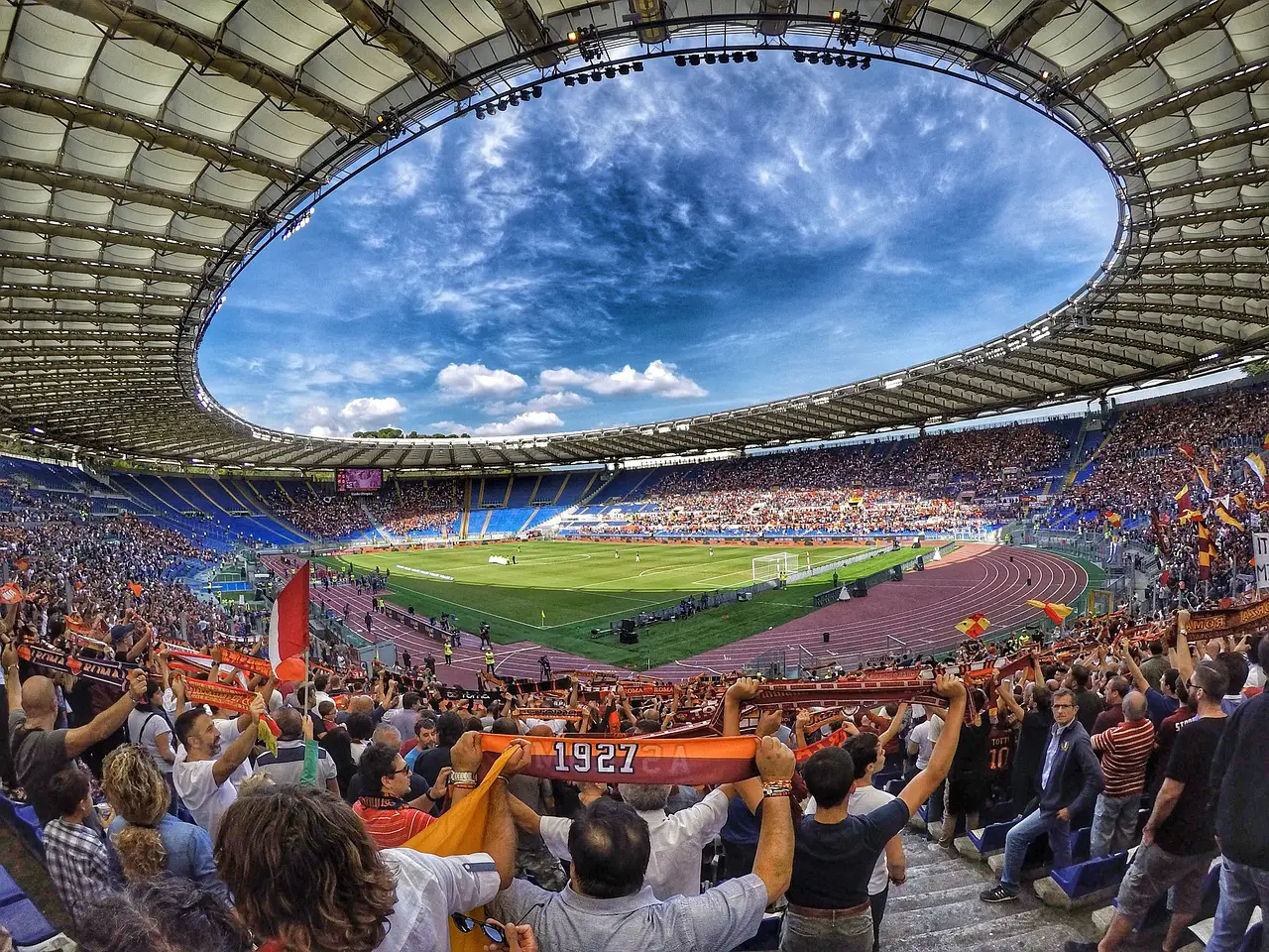 Sports travel enthusiasts cheering in a packed stadium during a football match.