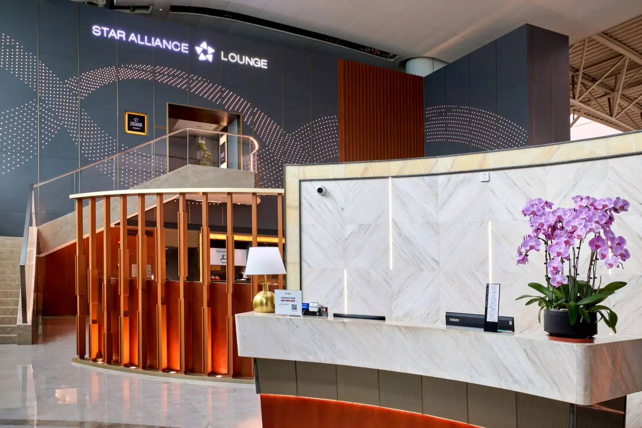 Entrance of the Star Alliance Lounge at Guangzhou Baiyun International Airport, featuring elegant modern design, illuminated signage, and a marble reception desk with a decorative orchid.