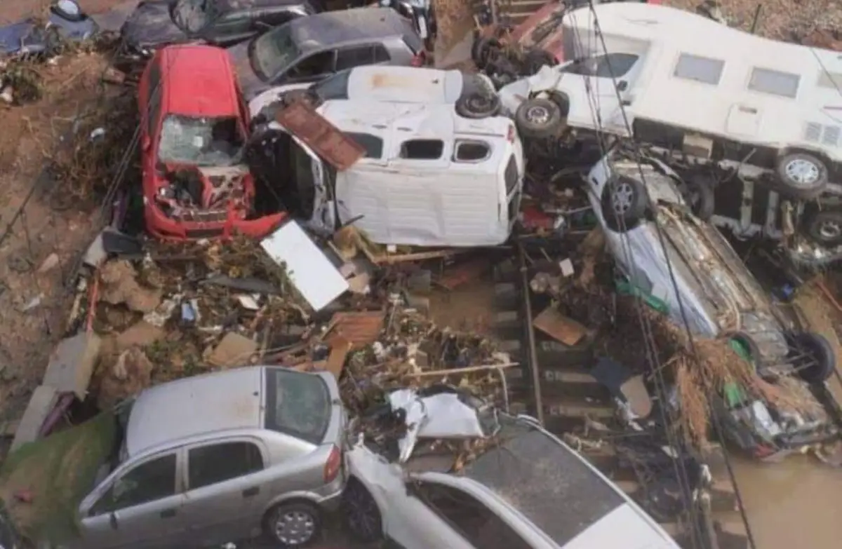 A pile of overturned and damaged cars on a flooded railway track after severe flooding.