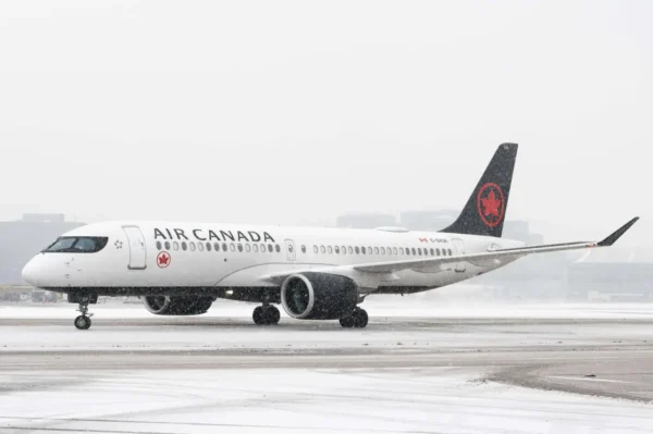 Air Canada Airbus A220-300 taxiing on a snowy runway.