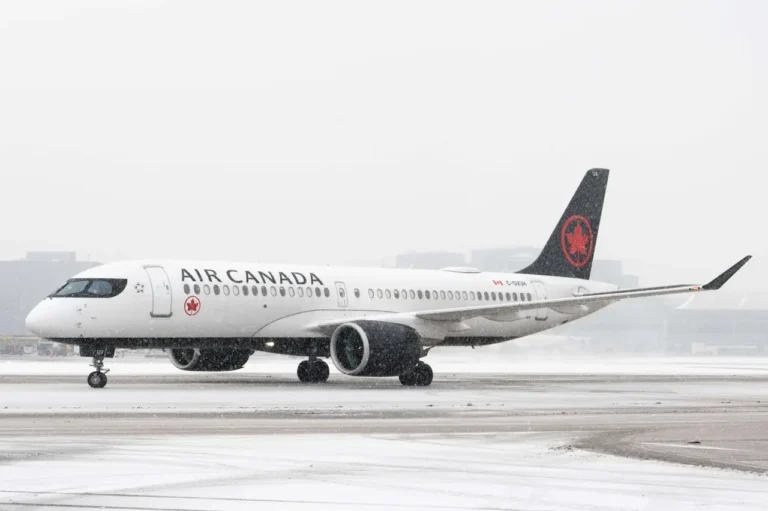 Air Canada Airbus A220-300 taxiing on a snowy runway.