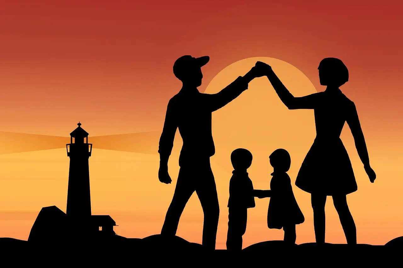 New Travel Insurance Plans You Didn’t Know You Needed 9 A silhouette of a family of four at sunset, with two adults high-fiving and two children holding hands, set against an orange sky and a lighthouse in the background.