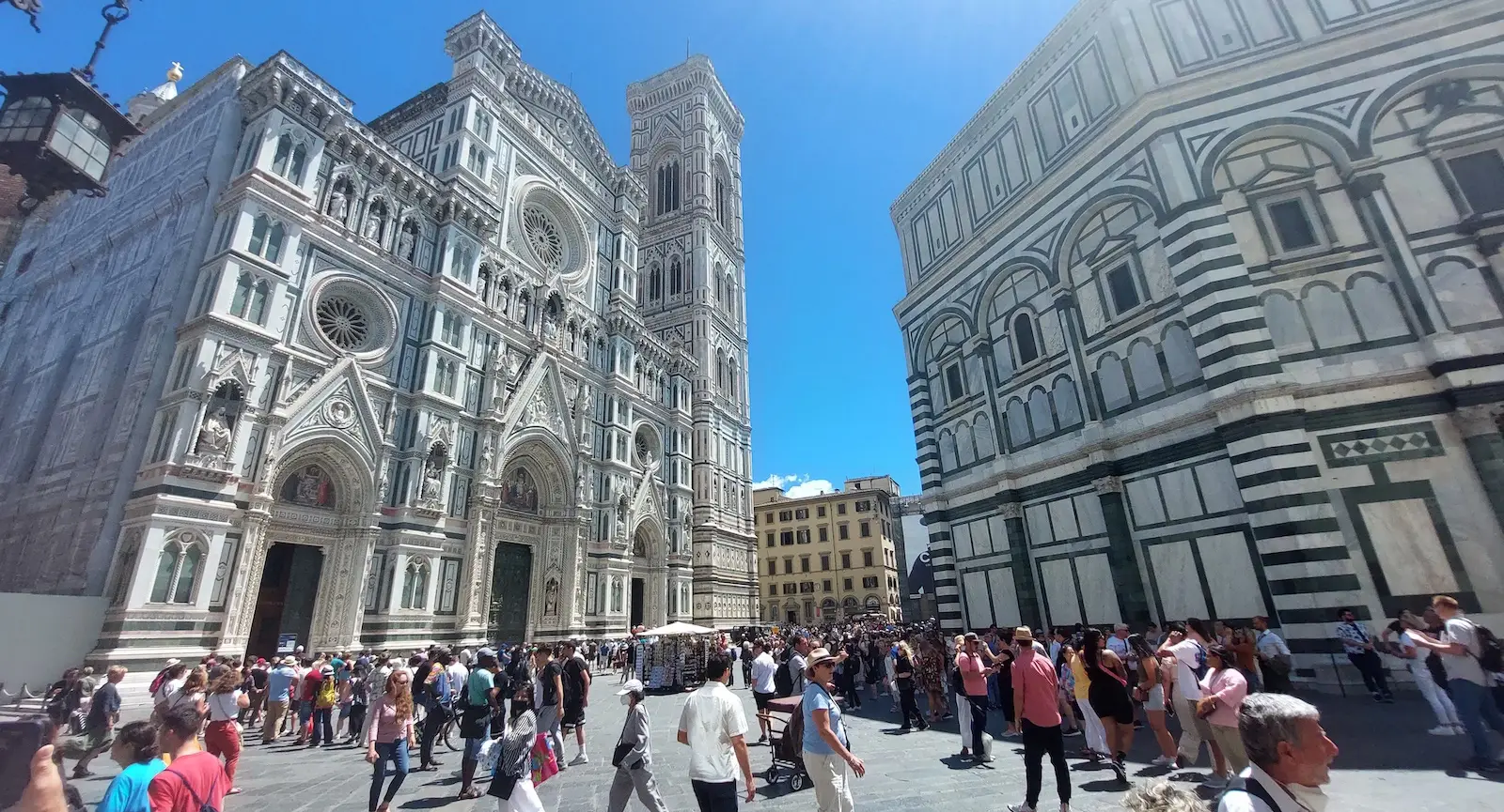 Florence Duomo with crowds of tourists in front under a clear blue sky.