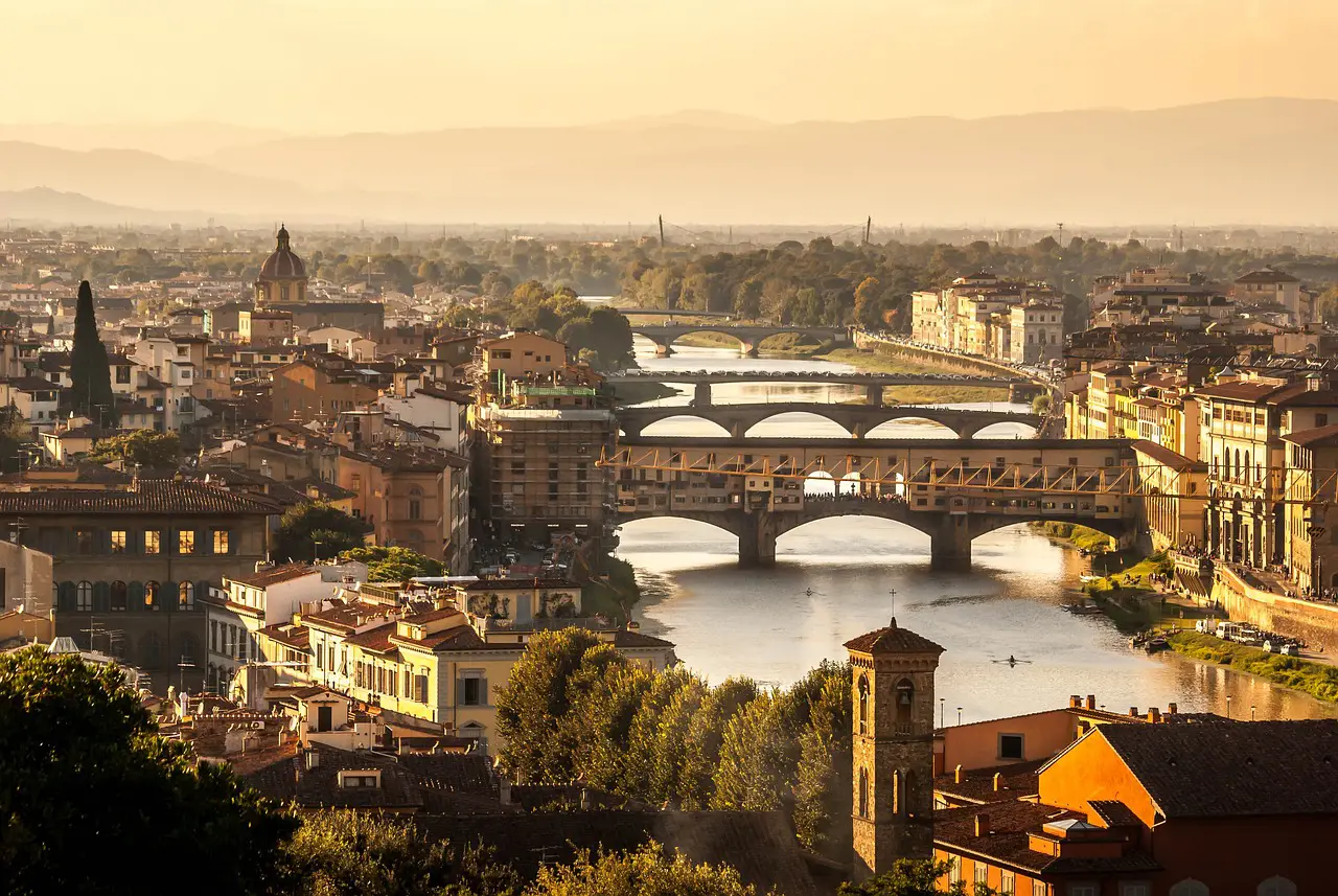 Florence cityscape at sunset with Ponte Vecchio spanning the Arno River.