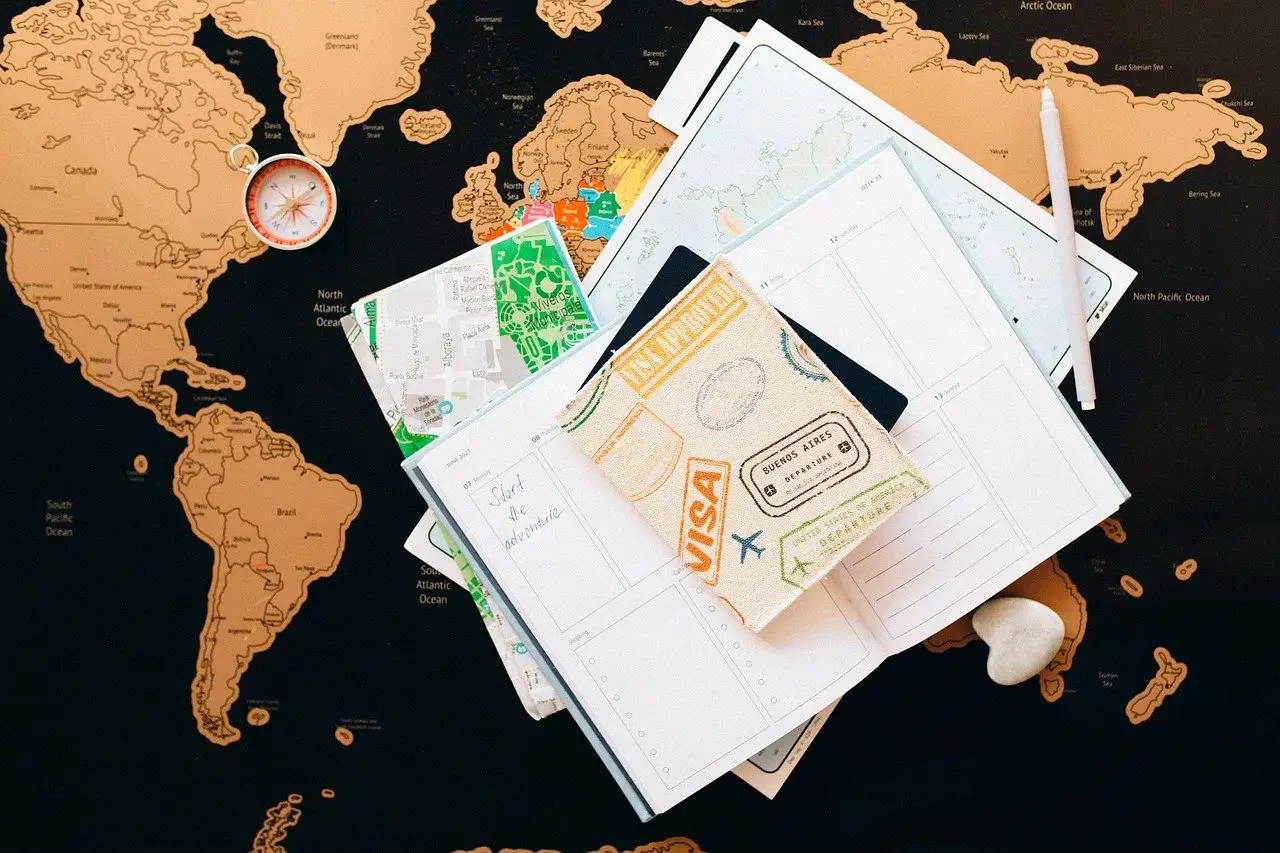 A world map with travel documents, a notebook, and a compass, symbolizing planning with the help of an international immigration lawyer.