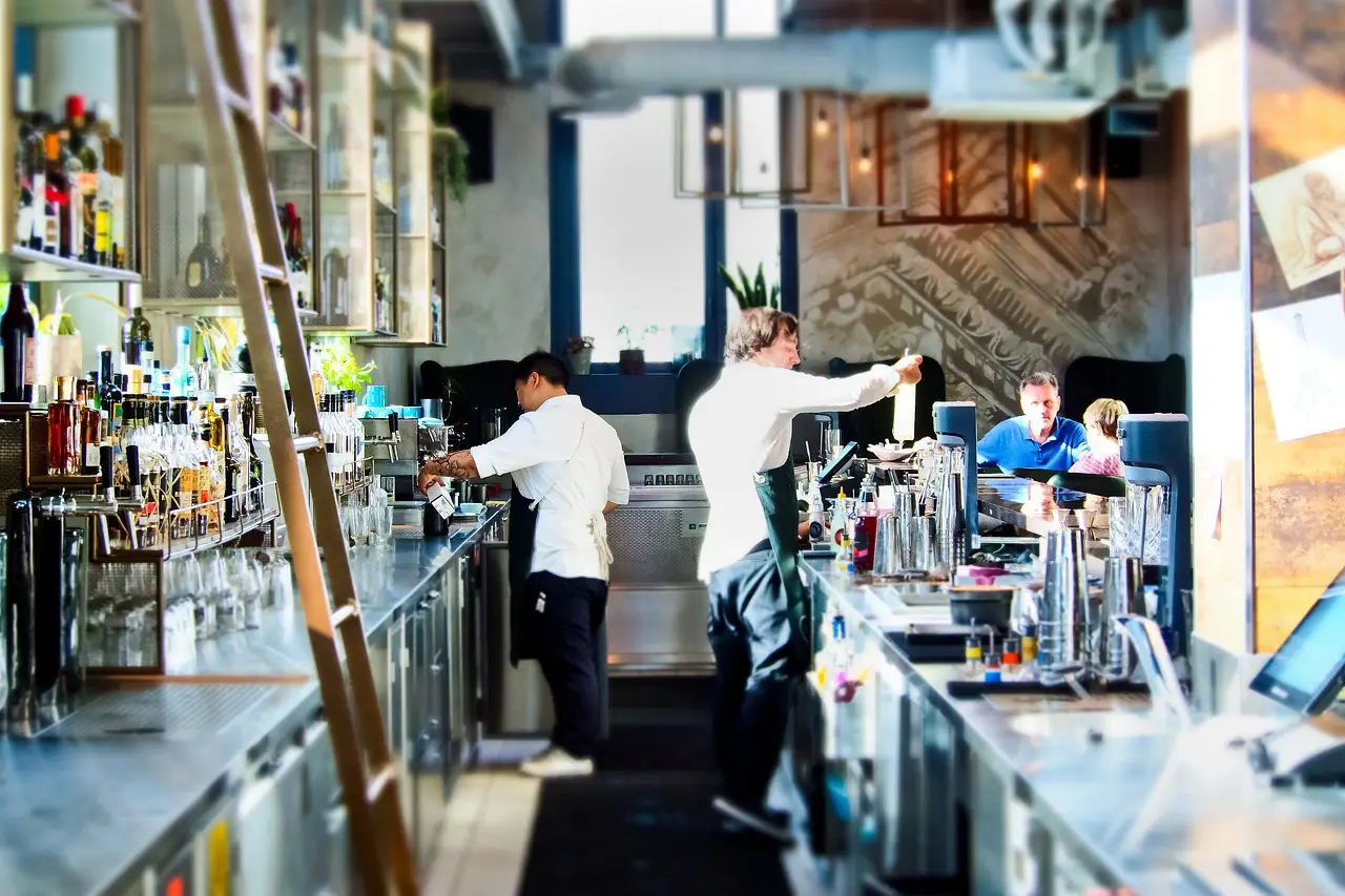 Bartenders working behind a modern bar, preparing drinks for customers seated in a lively atmosphere.