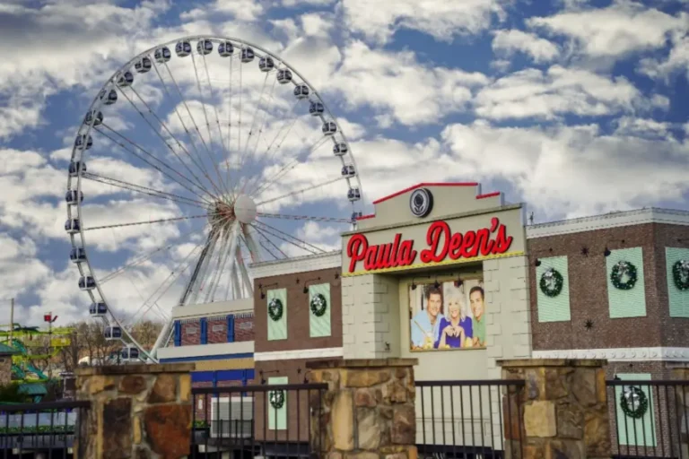The iconic Ferris wheel at The Island in Pigeon Forge rises behind Paula Deen’s Family Kitchen. Under a cloudy sky, it is adorned with festive holiday wreaths.