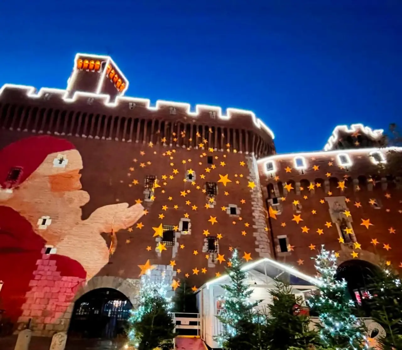 Christmas light projection of Santa and stars on a historic fortress in Perpignan, France.