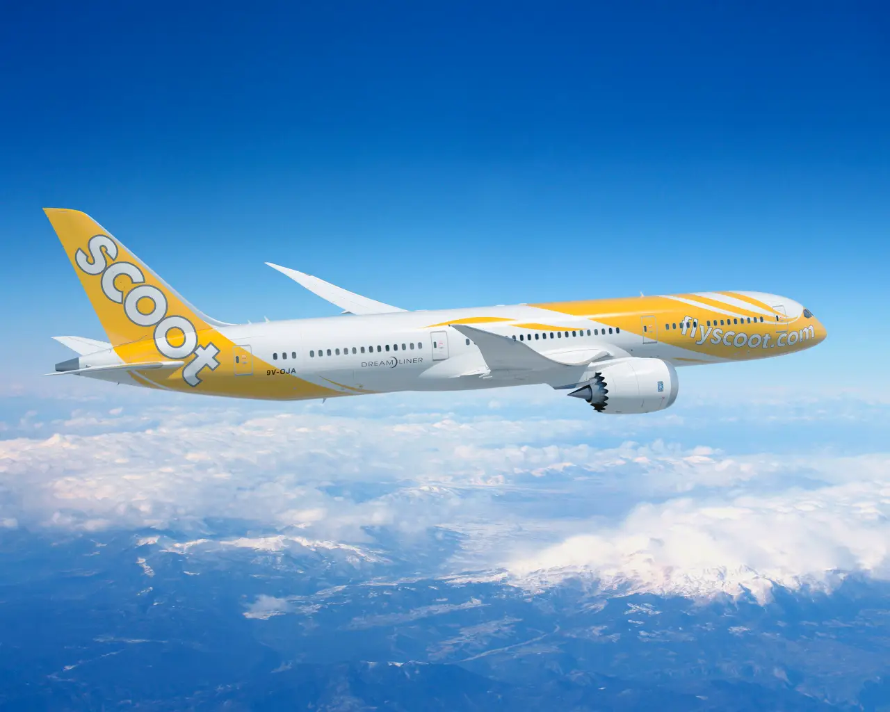 Scoot Airlines Boeing 787 Dreamliner flying above the clouds with a clear blue sky.