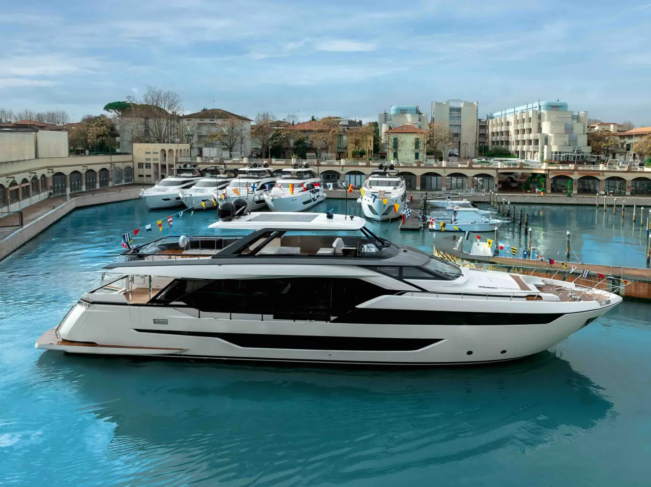 The newly launched Ferretti Yachts 940 docked at the Cattolica shipyard, surrounded by other luxury yachts in calm blue waters.