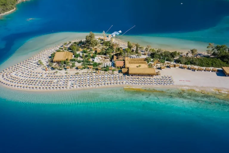 Aerial view of a beach in Marmaris with turquoise waters, sunbeds, and cabanas.