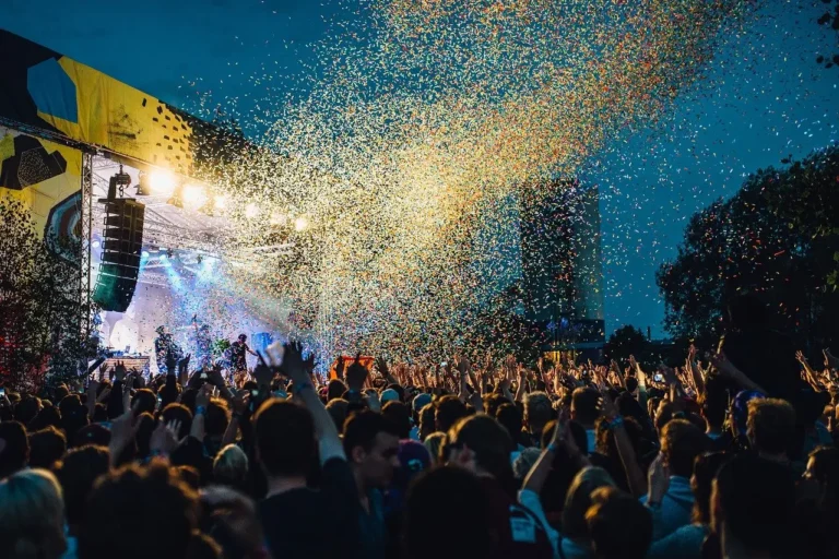 Tours 25 Music tourism: A vibrant festival crowd enjoying a live concert under a sky filled with confetti.