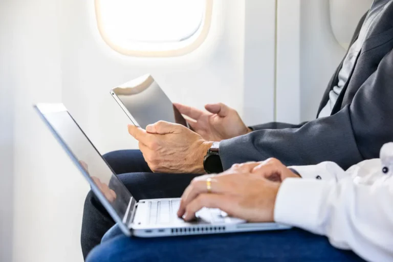 Technology 10 Passengers using a laptop and tablet while seated on an airplane, highlighting in-flight internet connectivity.