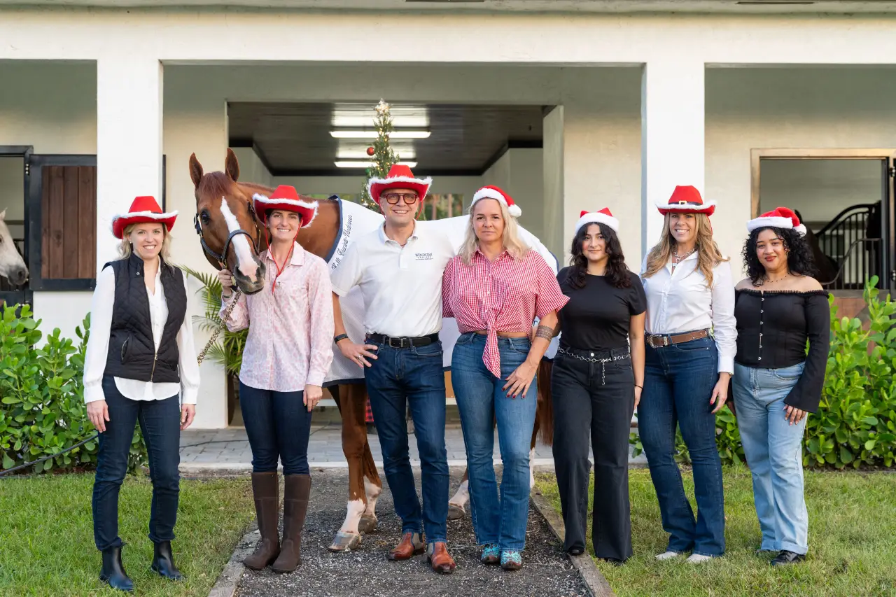 Windstar Cruises Ventures Into Equestrian Sports With Champion Horse Windstar 7 Windstar Cruises team and Kelli Cruciotti Vanderveen pose with Windstar the horse, all wearing festive Santa hats.