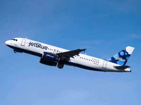 Home 15 A JetBlue Airbus A320 aircraft in flight against a clear blue sky.