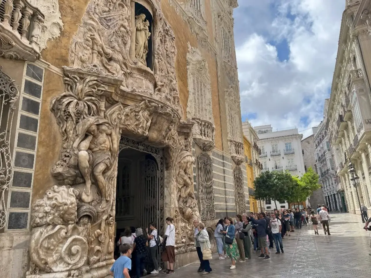 Visitors waiting in line outside the González Martí National Museum of Ceramics and Sumptuary Arts in Valencia, Spain, featuring an ornate Baroque-style entrance.