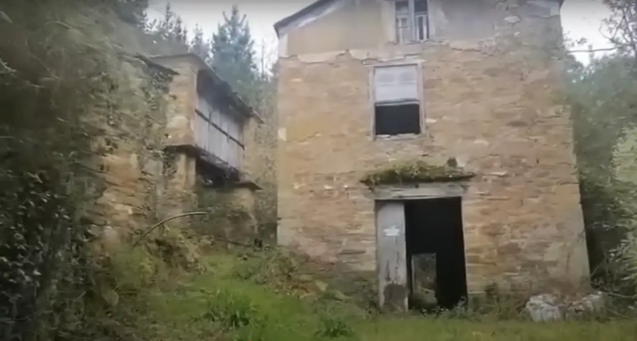 Dream Of Rural Life? Buy A Lugo Village Near Beaches For €65K 2 Abandoned stone houses in a rural village near Lugo, Spain, surrounded by overgrown vegetation.