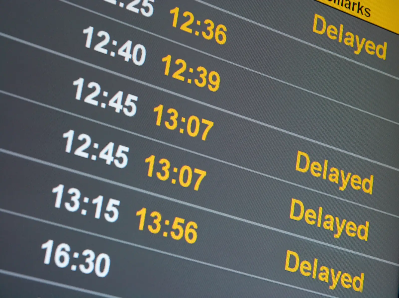 Close-up of an airport flight information board displaying multiple delayed flights.