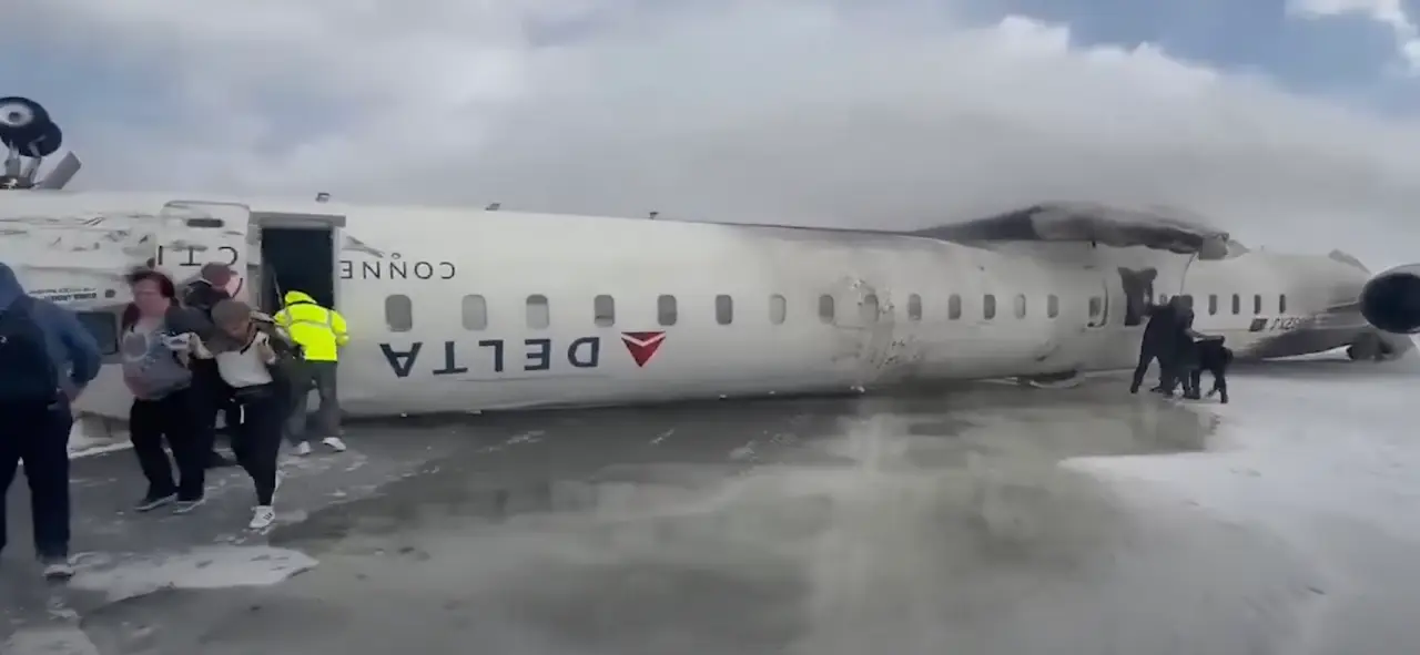 Passengers evacuate an overturned Delta plane on a snowy Toronto runway.