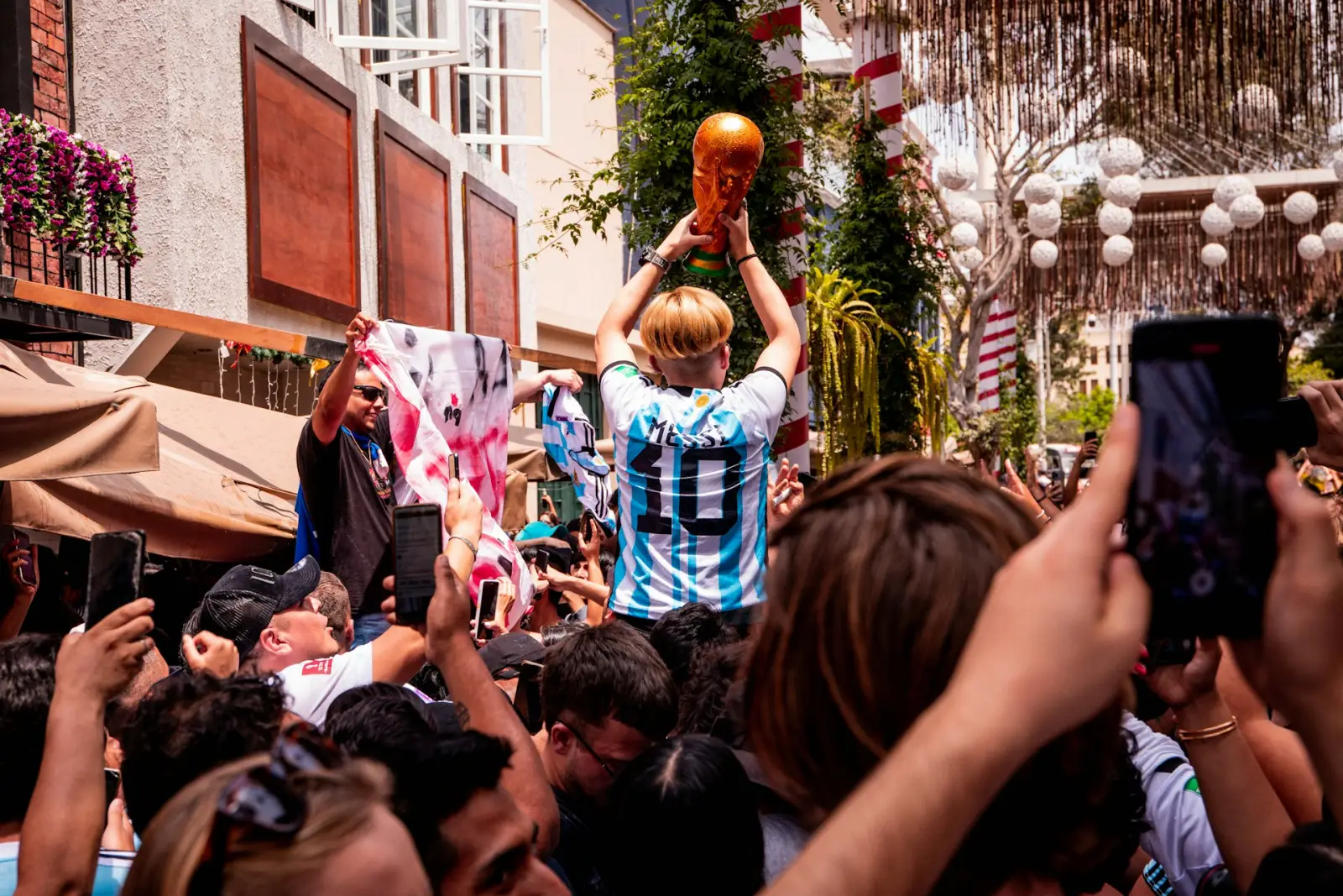 A crowd celebrating with a person holding a replica World Cup trophy.