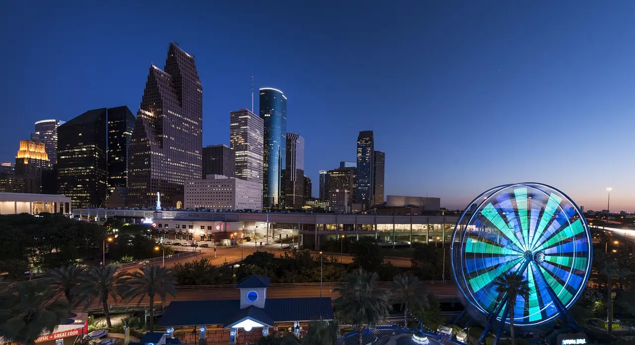 Houston skyline at night with illuminated Ferris wheel in the foreground.